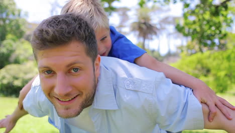 Father-giving-his-son-a-piggyback-with-his-arms-spread-as-he-smiles