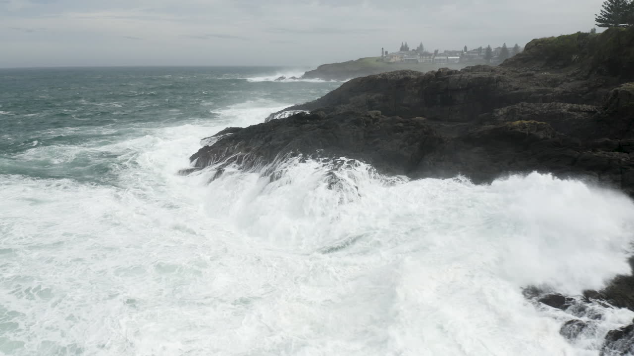 Fly around shot of angry ocean exploding onto the rocky shore line. Stormy weather.
