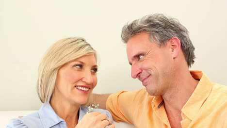 Husband-giving-his-wife-a-small-flower-on-the-couch