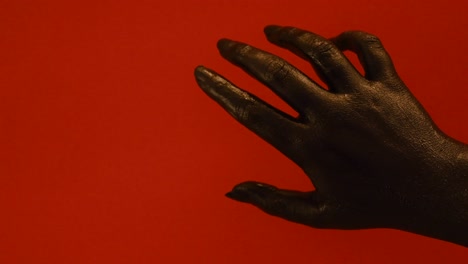 young female hand painted with black color moving smoothly in a red background