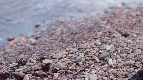 close up still shot of clear gentle water waves breaking on rocky shore