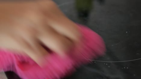 cleaning a kitchen cooktop with a pink cloth