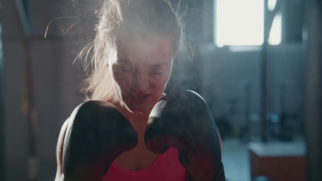 Giovane pugilessa che si allena in palestra con i guantoni da boxe