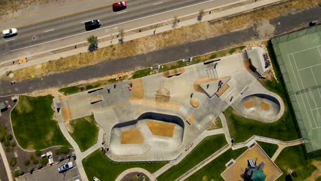 descending aerial spinning view of an urban skate park and activity center