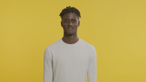 smiling man in white shirt against yellow background