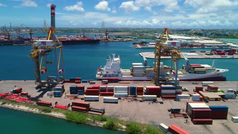 puerto de contenedores de envío, dos grúas y barco atracado, cielo azul cristalino día soleado curacao caribeño