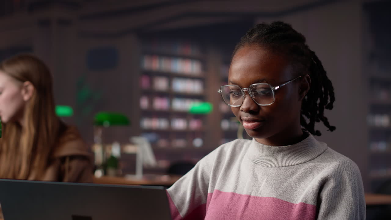 Vertikal video af sort studerende, der studerer på universitetsbibliotek til sin bacheloruddannelse.