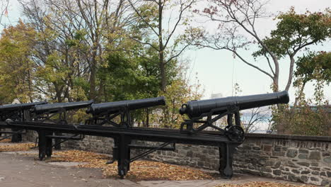 row of weathered iron cannons stand atop the stone ramparts of quebec city