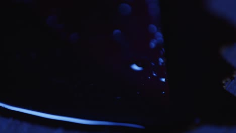 estrecho de la punta afilada del cuchillo de cocina en un charco de sangre con luces de la policía parpadeando en el fondo