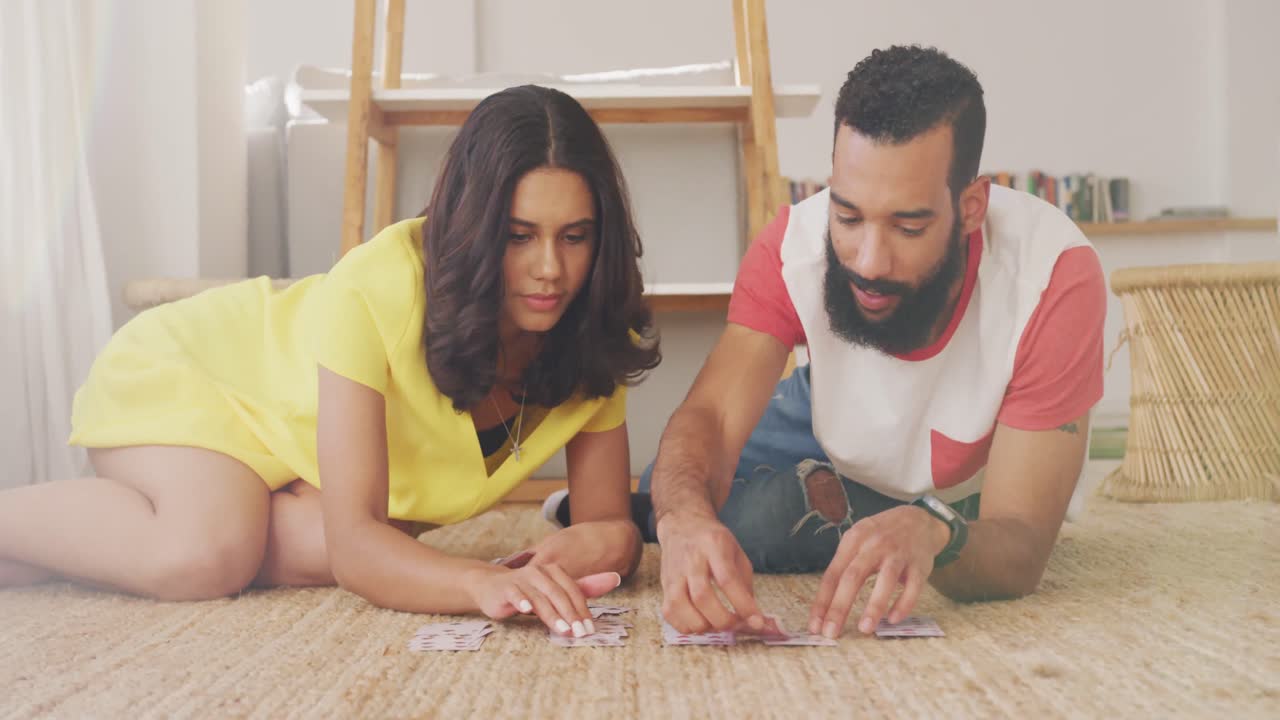 pareja feliz sonriendo mirándose el uno al otro y sonriendo mientras juegan a las cartas