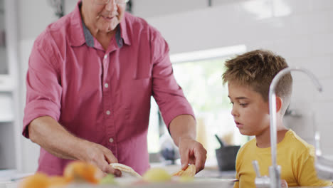 Feliz-Abuelo-Caucásico-Y-Nieto-Haciendo-Pizza-En-La-Cocina,-Cámara-Lenta