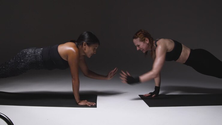 Studioaufnahme von zwei reifen Frauen in Sportkleidung, die gemeinsam eine Plank-Übung machen 1.