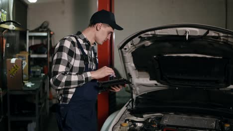 Mechanic-inspects-the-car-undercarriage-way-with-a-digital-tablet