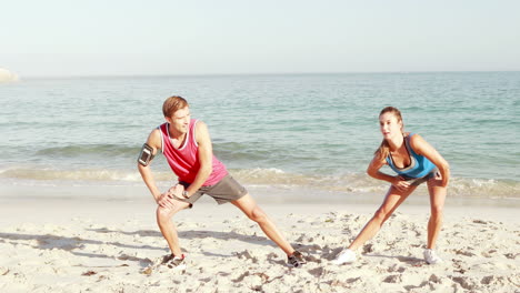 Smiling-couple-stretching-their-legs-on-the-beach