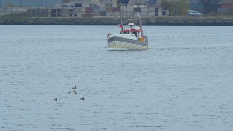 Kleines-Weißes-Küstenfischerboot-Verlässt-Den-Hafen-Von-Liepaja,-Bewölkter-Tag,-Fischer-Bereit,-Einen-Fisch-In-Einer-Ostsee-Zu-Fangen,-Lokales-Geschäft,-Entfernte-Mittlere-Aufnahme