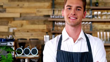 portrait of male waiter standing with arms crossed