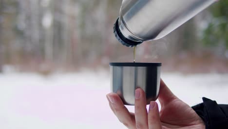 pouring hot tea from thermos in the snow