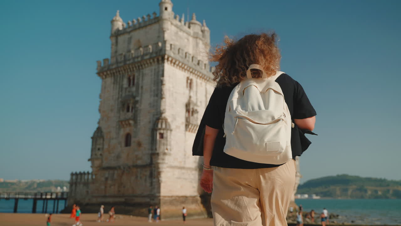 mujer caminando por la playa cerca de la torre de belém