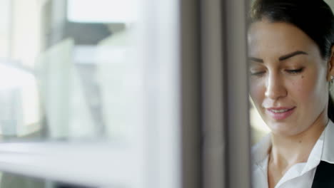 smiling businessman and businesswoman writing on sticky notes and giving high five when standing by glass wall in office