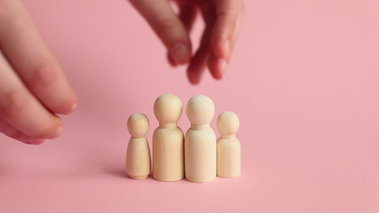 Female puts small figures on sides of large wooden figurines