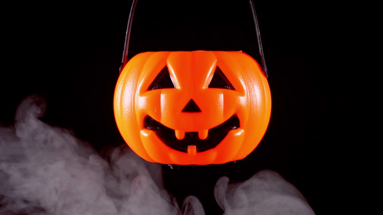 concepto de halloween - moviendo linterna de calabaza de plástico con humo blanco alrededor aislado en fondo negro oscuro, aterrador y estado de ánimo de horror.