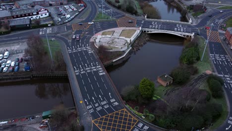 Aerial-early-morning-city-street-traffic-commuting-intersection-lanes-crossing-curved-river-birdseye-descending