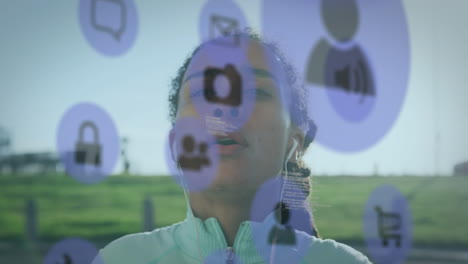 video compuesto digital de iconos digitales flotando contra una mujer afroamericana que usa auriculares