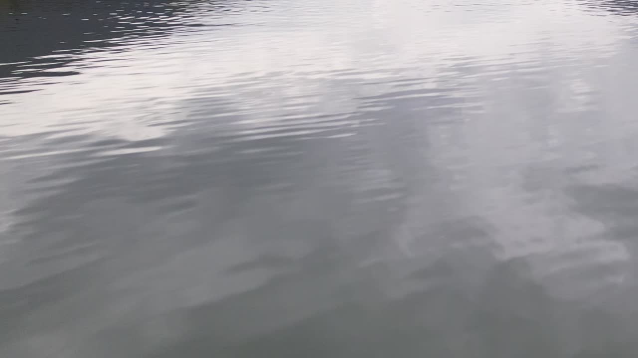 Drone captures serene alpine lake reflecting cloudy sky in Italy