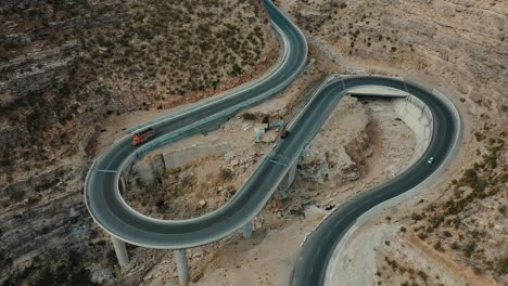 aerial over new winding cpec road at fort munro in pakistan with truck and car passing through