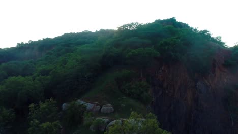 Disparo-De-Drone-Que-Muestra-El-Movimiento-Hacia-Arriba,-Revelando-El-Sol-Poniente-Con-Una-Llamarada-Solar-Y-Un-águila-Volando-Sobre-La-Montaña