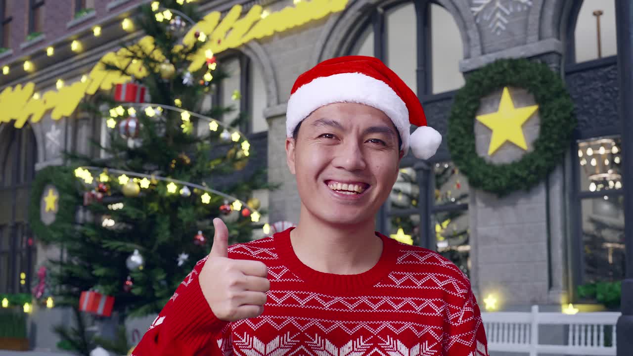 산타 모자를 입은 남자가 크리스마스 장식품 앞에서 엄지손가락을 올리고 있다