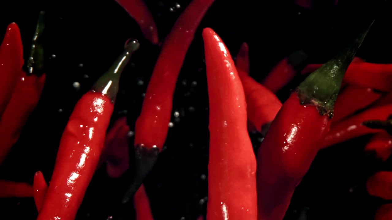Red Chili Peppers Floating in Water on Black Background
