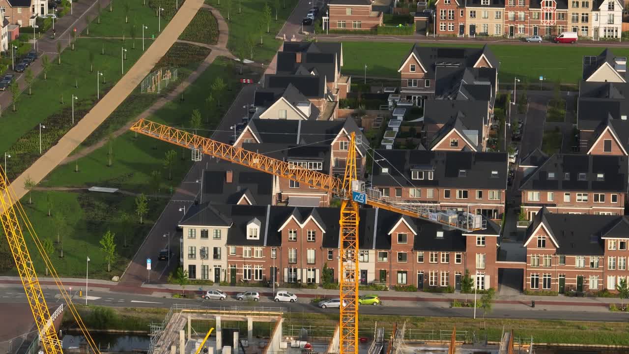 vista aérea de órbita media de una grúa torre amarilla que construye un nuevo desarrollo habitacional en la ciudad de weesp, cerca de ámsterdam, países bajos