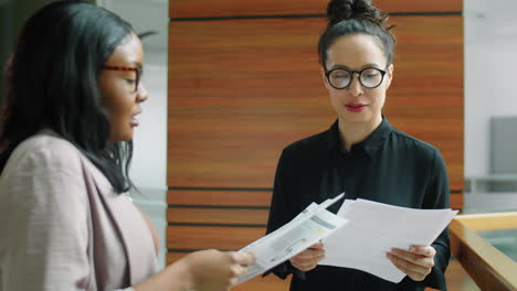 mujeres de negocios multiétnicas leyendo documentos y hablando