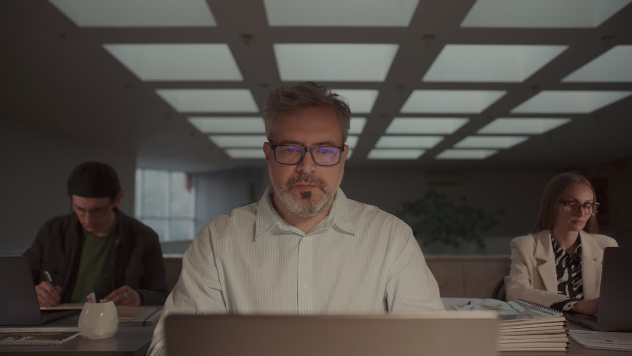 Mid-Aged Businessman Focusing Deeply on Laptop Screen at Office Desk