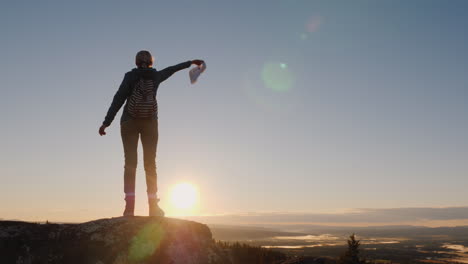 woman traveler waving a cap at the top of the mountain success and active holidays in norway