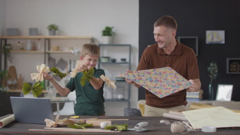 father and son making a kite together at home