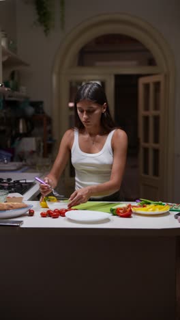 woman preparing a salad in a kitchen at night