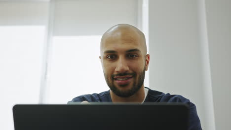 Smiling bald man working on laptop