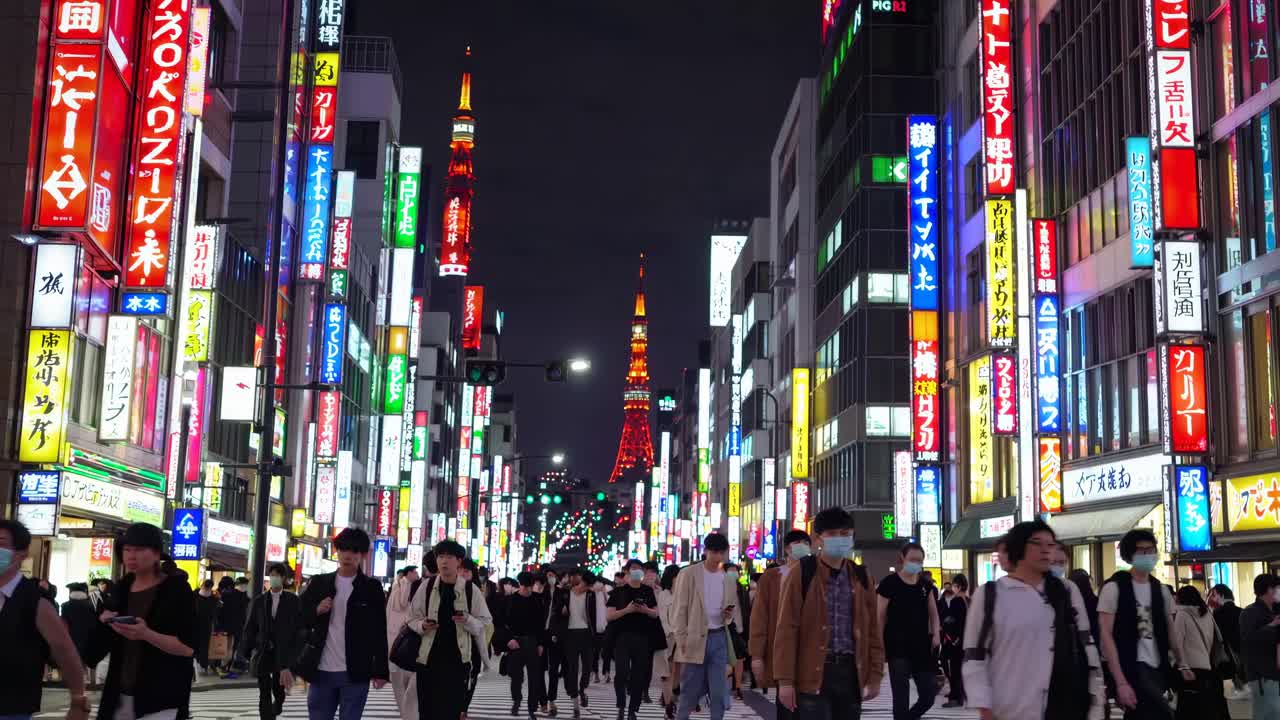 Street-level video capture of a bustling city at night, featuring vibrant neon signs and a distant