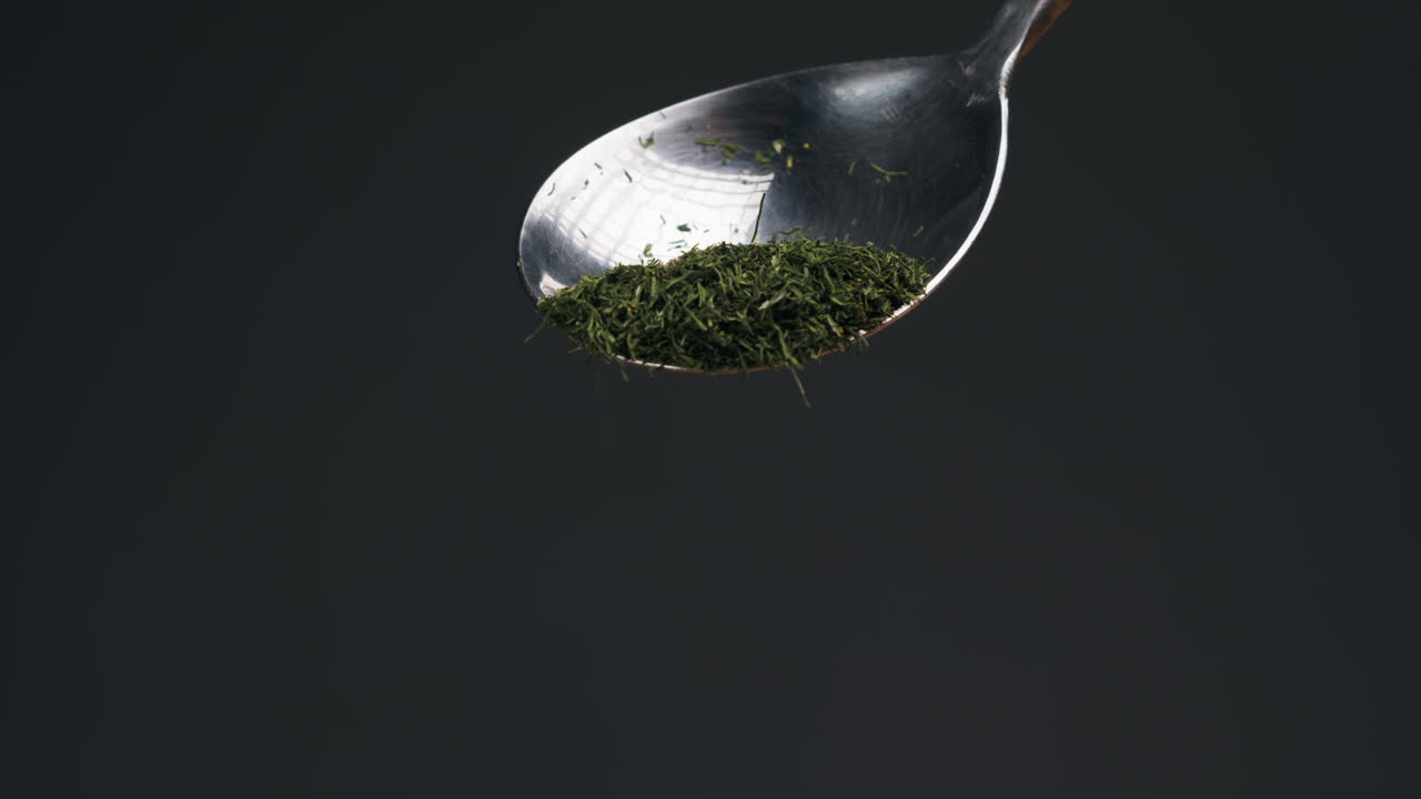 Dried green dill on spoon close-up macro. Spice for food. Man hand strewing dill on food . High quality 4k footage