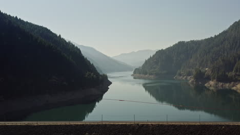 le camping-car voyageant à travers le barrage surplombant le réservoir de cougar avec des montagnes et de la brume en arrière-plan