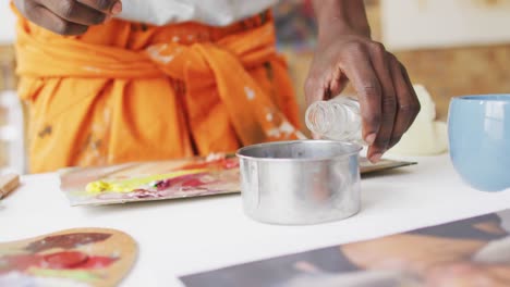 midsection of african american male painter mixing paint in artist studio