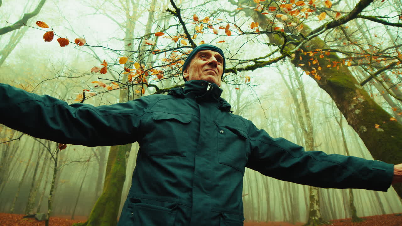 Elderly Man Doing Relaxation Breathing Exercises in Foggy Autumn Mountains