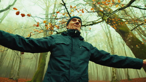 elderly man doing relaxation breathing exercises in foggy autumn mountains