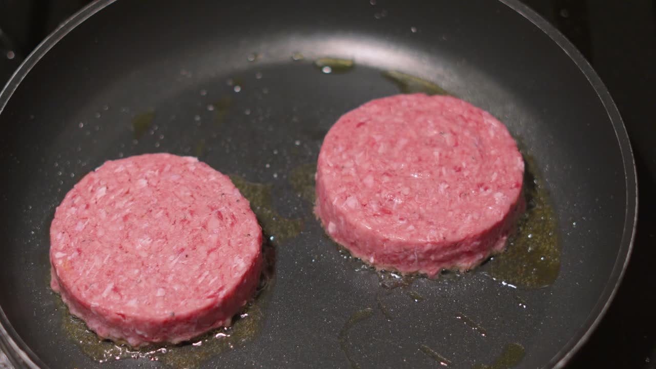 Top Moving View of Pink Raw Beef Burgers Starting to Fry in Hot Pan. Fresh Meat Food Preparation