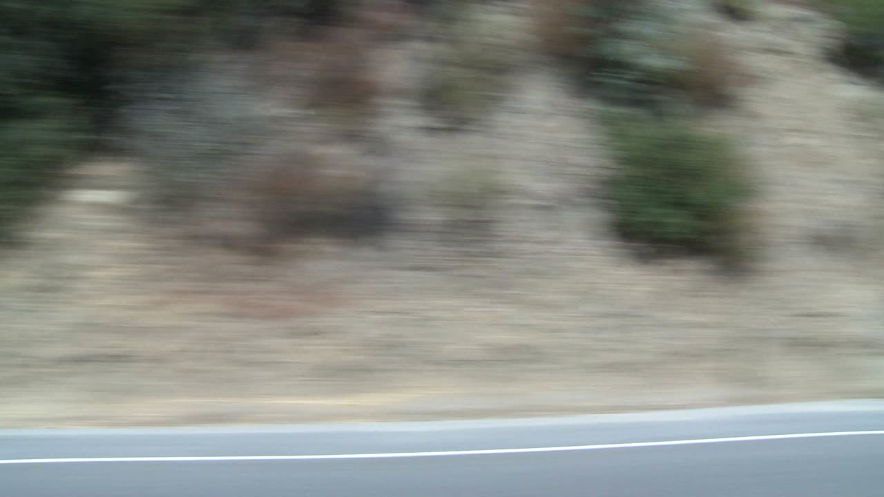 측면 창 1을 통해 보이는 로스앤젤레스 캘리포니아 근처의 경치 좋은 고속도로를 따라 차가 이동합니다.