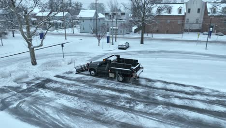 pickup truck with dump bed and snow plow clearing snow covered parking lot