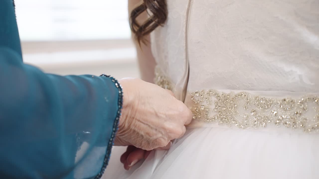 Woman's Hand Zipping Up Back of Bride's Wedding Dress