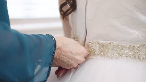 woman's hand zipping up back of bride's wedding dress